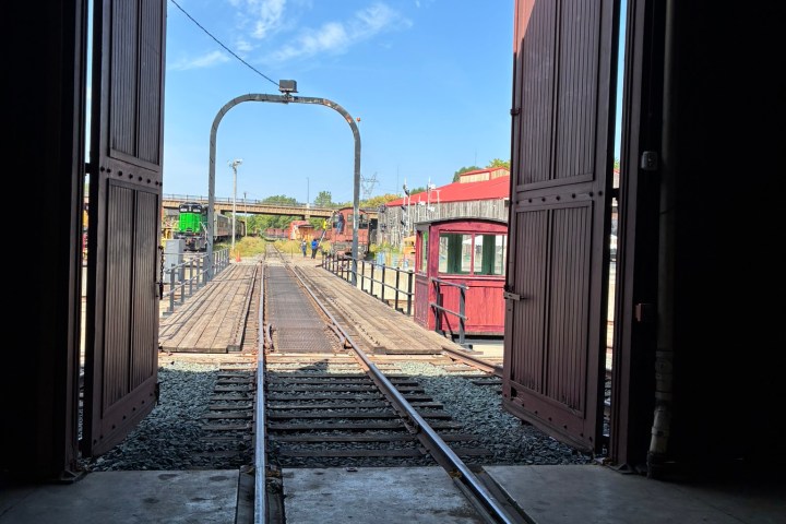 View through open doors to a railway track with a clear blue sky.