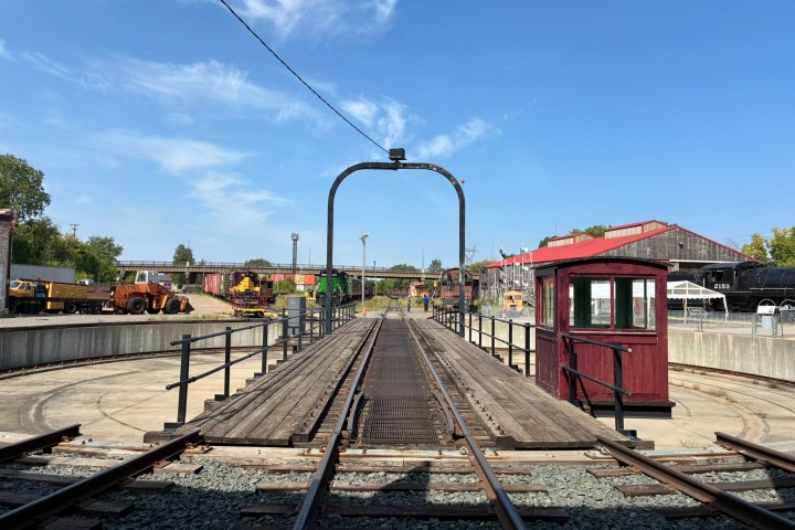 Railway turntable with red control booth under a clear blue sky.