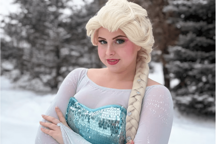 Person in a light blue dress with braided blonde hair, standing in snowy landscape.